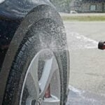 Reifen eines Autos werden mit Wasserschlauch abgespritzt