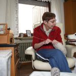 Rita Steffen (57) sitzt in ihrem Haus an ihrem elektrischen Spinnrad, um aus Hundehaaren Wolle herzustellen. Neben ihr ist die weiße Schäferhündin Finja zu sehen. Foto: dpa-Bildfunk/Katja Sponholz