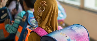 Ein Mädchen mit Kopftuch steht in einer Schule vor einem Klassenzimmer. Symbolfoto: dpa-Bildfunk/Wolfram Kastl