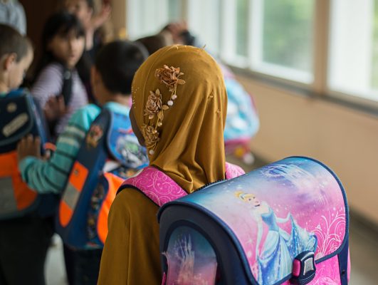 Ein Mädchen mit Kopftuch steht in einer Schule vor einem Klassenzimmer. Symbolfoto: dpa-Bildfunk/Wolfram Kastl