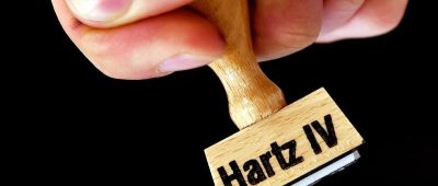 Eine Hand hält einen Stempel mit der Aufschrift "Hartz IV". Foto: Ralf Hirschberger/Archiv