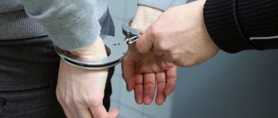 Ein Polizist legt einem Festgenommenen Handschellen an. Symbolfoto: Pixabay