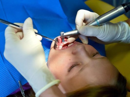 Ein siebenjähriges Mädchen wird von einer Zahnärztin behandelt. Foto: Patrick Pleul/Archiv