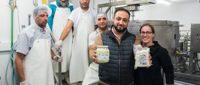 Abdul Saymoa zeigt gemeinsam mit einem Team und Geschäftspartnerin Anna Riehm (r) seinen Käse. Foto: Oliver Dietze/dpa-Bildfunk