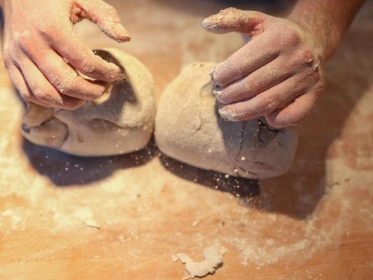 Ein Bäcker formt mit seinen Händen zwei Brote. Foto: Jan Woitas/dpa-Zentralbild/dpa/Symbolbild