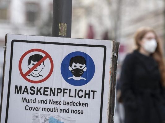 Plakate erinnern in einer Fußgängerzone an die Einhaltung der Maskenpflicht. Foto: Boris Roessler/dpa